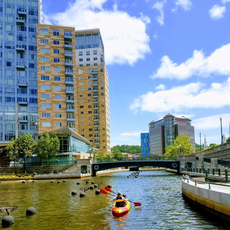 a small boat in a body of water with a city in the background