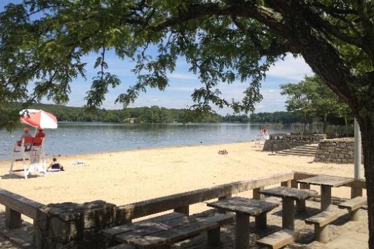 a row of wooden benches sitting on top of a sandy beach
